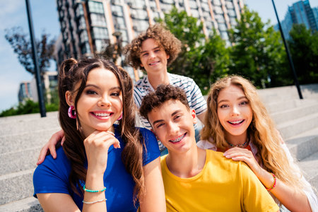 Happy young friends enjoying a sunny day outdoors together with a vibrant modern cityscape in the...
