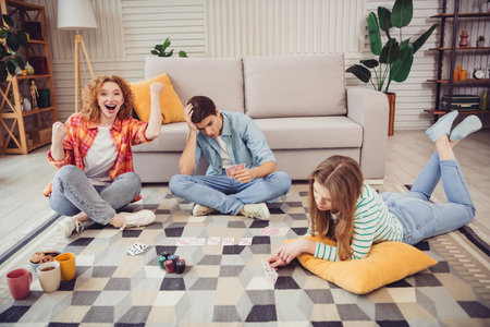 Positive friends enjoying a indoor game of cards at home, creating joyful memories and strengthening their bond on a bright afternoonの写真素材