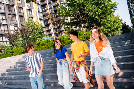Group of young friends energetically walking outdoors in a city area enjoying a sunny day and building memoriesの写真素材