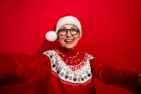 Festive woman in red sweater and santa hat posing with joy against vibrant background brimming with...