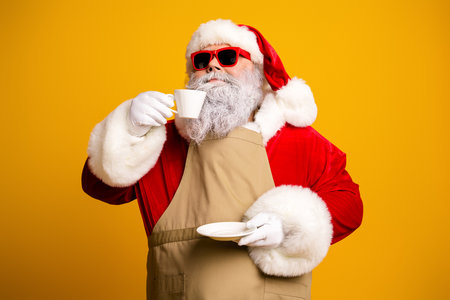 Santa Claus enjoying a cup of coffee with a modern flair and funky sunglasses against a vibrant yellow backgroundの写真素材
