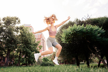 Energetic woman jumping outdoors in sporty wear celebrating fitness and healthy living