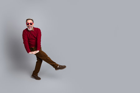 Middle-aged man in a casual red sweater poses joyfully against a blank gray background, showcasing...
