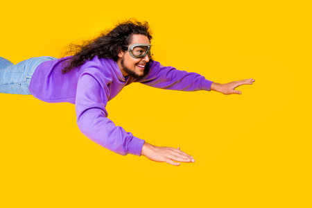 Young man in purple hoodie posing on yellow background with a joyful expression conveying energy and...
