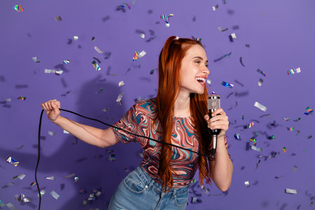 Young woman singing with joy in front of colorful confetti and purple background, showcasing vibrant emotion and styleの写真素材
