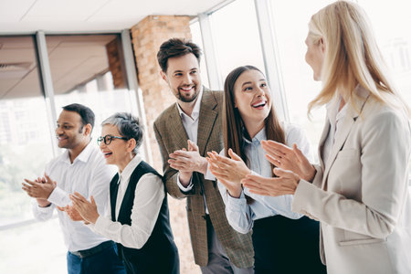 Happy team of diverse professionals clapping in a modern office celebrating success and teamwork