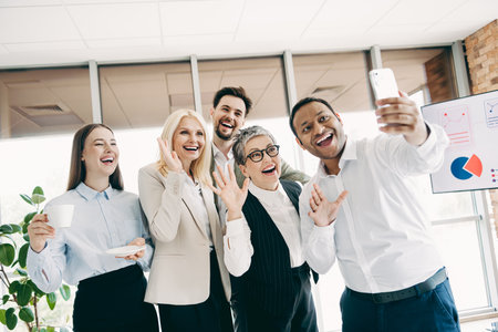 Group of professional colleagues capturing cheerful moments during a business gathering in a bright,...