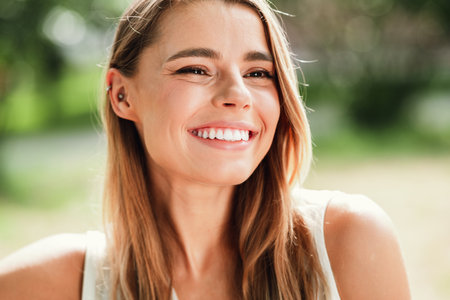 Smiling blonde woman outdoors on a sunny day in the park a vibrant lifestyle portrait for advertising and travel campaignsの写真素材