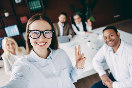 Cheerful office team collaborating at the workspace while capturing a casual group selfie together, promoting teamworkの写真素材
