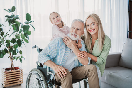 Family bonds as granddaughter hugs grandfather in a bright home setting with a smiling mother nearby in a cheerful living room sceneの写真素材