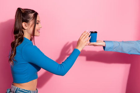 Cheerful woman in vibrant blue top receiving small coffee mug with happy expression against bright pink backgroundの写真素材