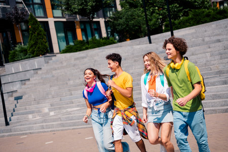 Group of diverse young friends enjoying a sunny day outdoors together, smiling and bonding in a casual urban setting.の写真素材