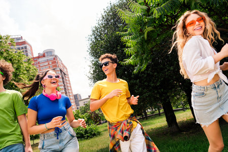 Group of cheerful young friends walking outdoors in a sunny park, wearing casual colorful outfits,...