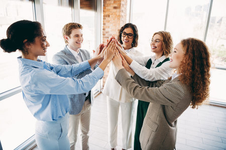Professional team celebrating collaboration in a modern office environment through teamwork and...