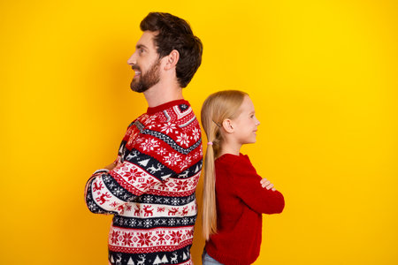 Joyful young family in bright sweaters share a joyful moment together against a yellow backdrop celebrating seasonal traditions.の写真素材