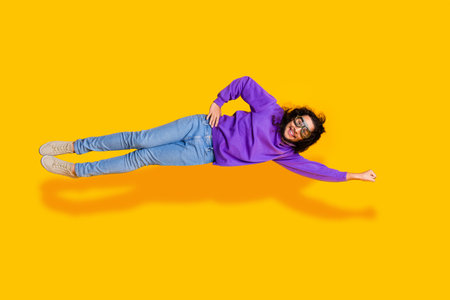 Young man in purple hoodie posing creatively on yellow background, showcasing casual sportswear...