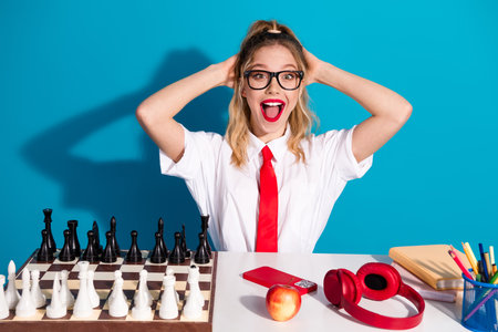 Stylish young woman posing with educational items on blue background showcasing playful and trendy student lifestyleの写真素材