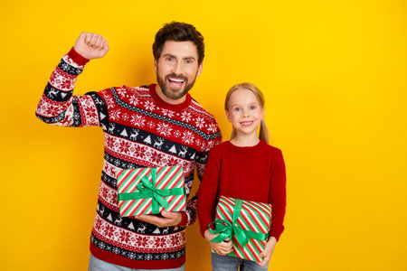 Father and daughter joyfully celebrating holidays, wearing festive sweaters and holding gift boxes...