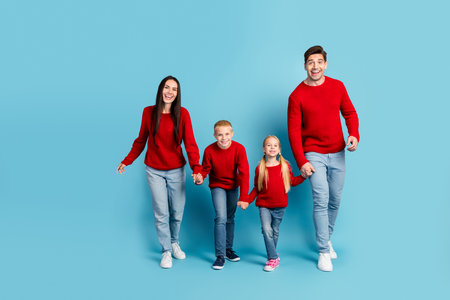 Cheerful family in matching red sweaters enjoying moments together on a vibrant blue background,...