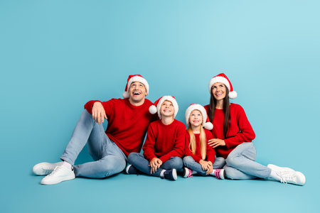 Happy family wearing Santa hats and red sweaters celebrating Christmas together on a cheerful winter...