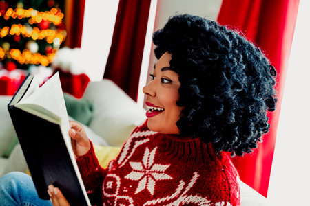 Woman enjoying a Christmas book by the tree in a cozy sweater, radiating festive joy and winter...