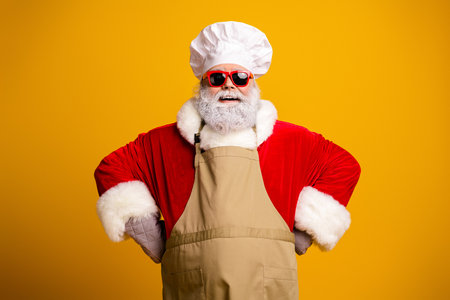 Festive Santa Claus Dressed as a Chef in Colorful Costume Against a Yellow Background with Fun and Cool Vibeの写真素材