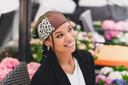 playful stylish woman in leopard scarf smiles at flowers in urban cafe scene with chic blazer and sunny vibeの写真素材