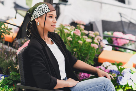 Relaxed stylish woman enjoys a sunny garden cafe moment in casual chic fashion and comfortの写真素材