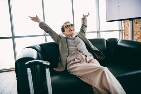 Professional businesswoman enjoys a moment of relaxation in a modern lounge, embracing positivity and successの写真素材
