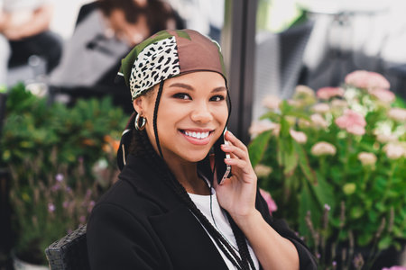 playful business style portrait of a smiling woman on the phone in an outdoor cafe setting for...