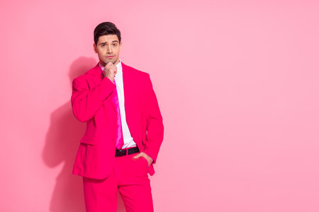 Attractive young man in stylish bright pink suit posing against matching color background with confident expressionの写真素材