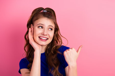 Young woman joyfully gesturing with her hand against a vibrant pink background, showcasing cheerful charismaの写真素材