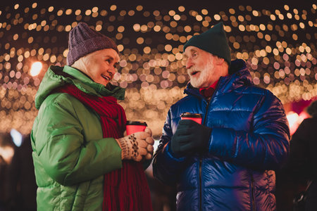 A funny winter moment with a loving couple sharing coffee under festive city lights and laughing...