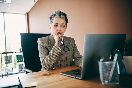 Professional Senior Businesswoman Working on Laptop in Office Environment Focused on Careerの写真素材