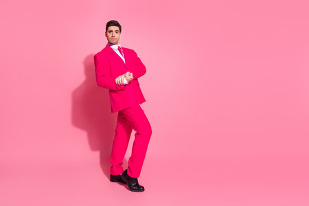 Charming young man in a vibrant pink suit posing elegantly against a matching pink background with a confident and stylish demeanorの写真素材