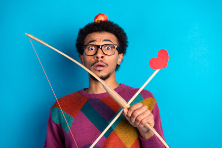 Man with a red heart and bow looking surprised on a blue background, expressing humor and lifestyle