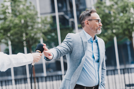 Professional businessman in a modern city interviewed outdoors in a confident stylish suit and elegant blazer representing business and real estate in a bustling urban street sceneの写真素材