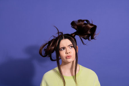 Funny millennial woman posing on purple background with unique hairstyle in casual outfit showcasing...
