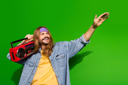Young man with long hair holding retro radio enjoying vibrant backgroundの写真素材