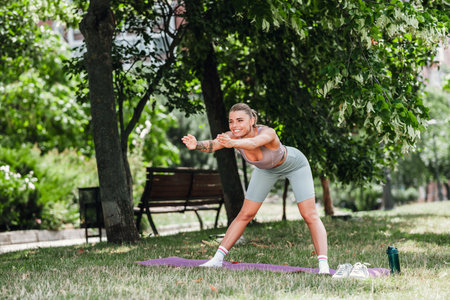 Outdoor fitness training in the park a young woman stretching on a purple matの写真素材