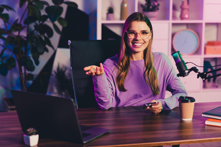 Young woman blogger in casual style presenting a live podcast from home office using microphone and laptopの写真素材
