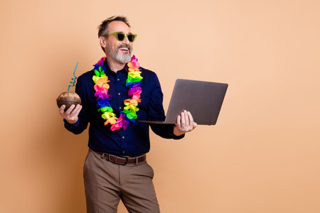 Businessman in colorful leis holding a laptop and coconut drinkの写真素材