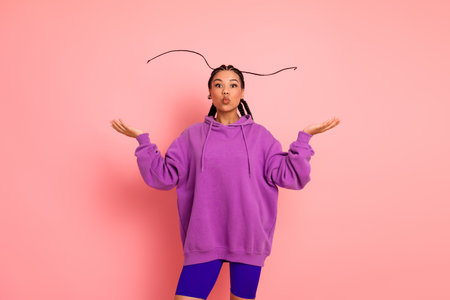 Young Woman Expressing Joyful Energy in Bright Sportswear with Stylish Braids Against a Vibrant Pink Backgroundの写真素材