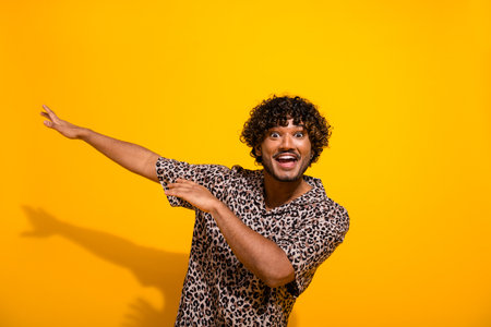 Excited young man in leopard print shirt posing energetically against a yellow background with a cheerful expressionの写真素材
