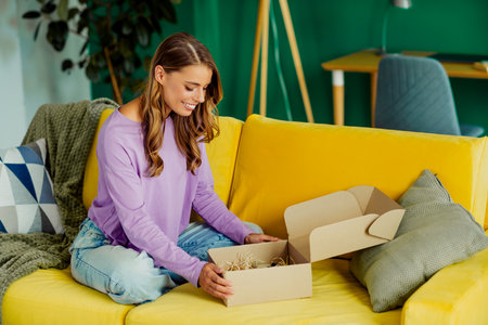 Smiling young woman happily unboxing in a modern living space, enjoying her leisure day on a vibrant...