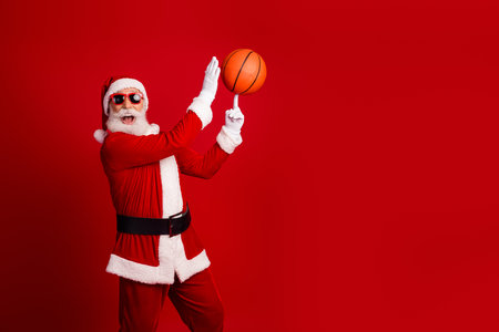 Santa Claus performing a fun basketball trick on a vibrant red background celebrating Christmas joyの写真素材