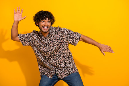 Handsome young man wearing leopard print shirt poses stylishly with yellow background, expressing playful enthusiasmの写真素材