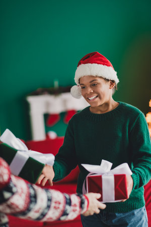 Festive moment of boy exchanging gifts near cozy Christmas interior filled with joyful decorations and holiday spiritの写真素材