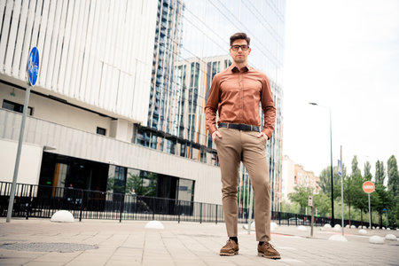Confident young businessman in formalwear standing in an urban setting with modern buildings in the backgroundの写真素材