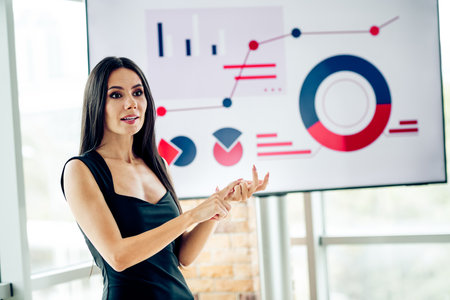 Professional businesswoman presenting data with charts and graphs in a corporate office environmentの写真素材